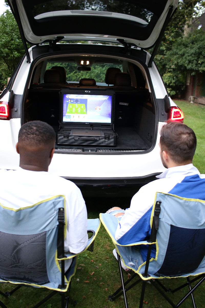 Person interacting with a car's open trunk, showing a screen inside.