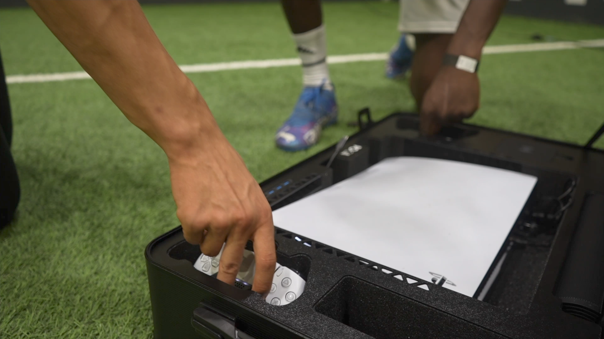 Person playing a black electronic device on a sports field