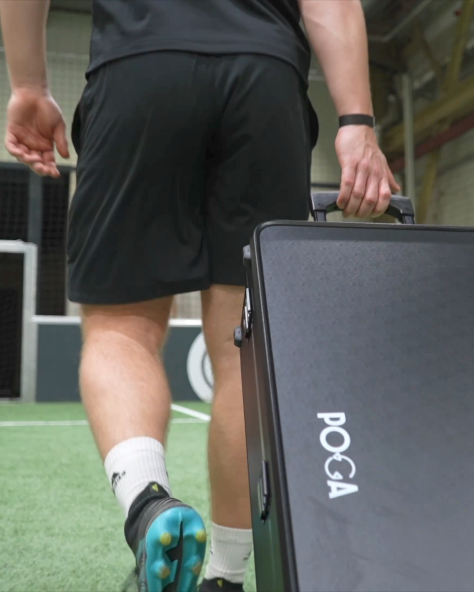 Person walking with a black gaming suitcase on a sports field