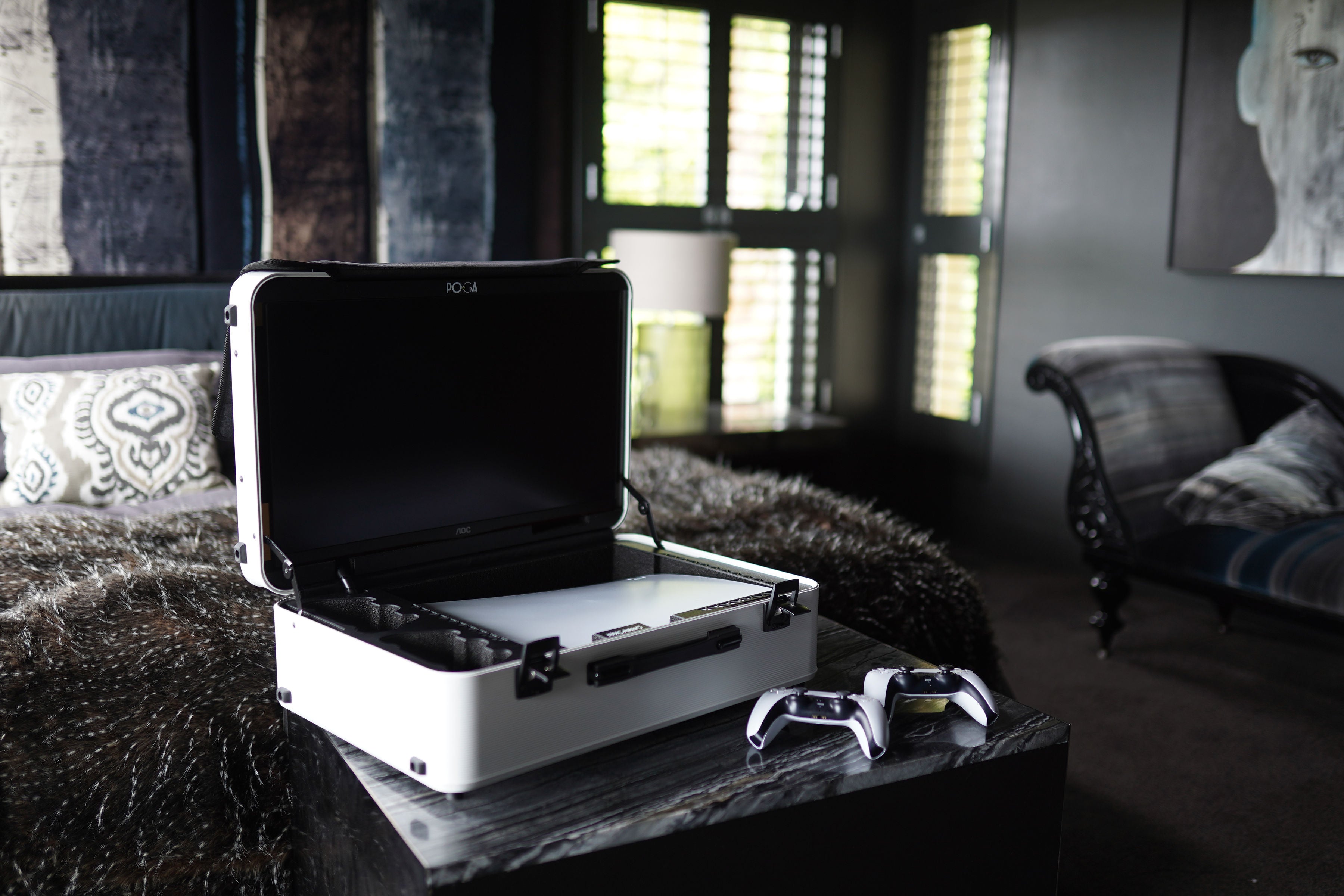 Portable gaming console with controller on a dark surface in a room with windows and furniture.